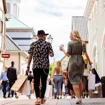 Bezoekers lopen samen door een winkelstraat bij Designer Outlet Roermond met sho